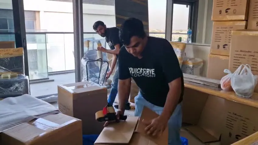 QuickServe crew members taping cartons during an apartment move in Dubai