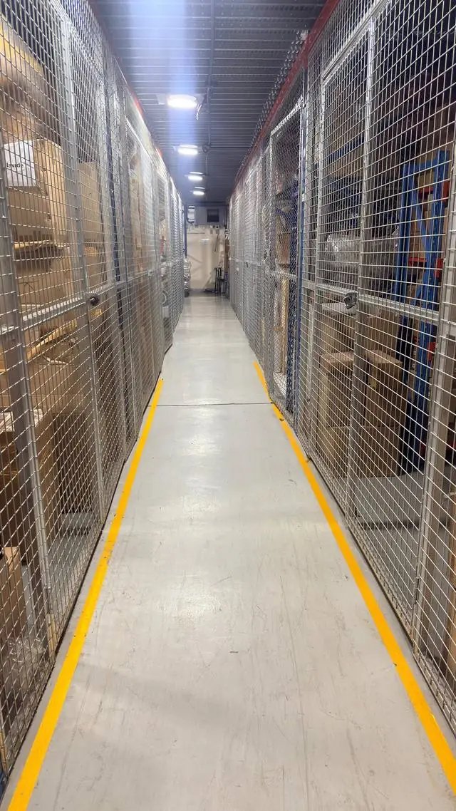 Wire-mesh storage cages along a marked aisle in a QuickServe storage warehouse in Dubai